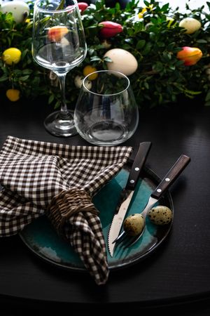 Easter table setting with delicate spotted eggs on ceramic teal plate and tulip centerpiece