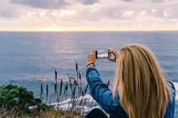 Female tourist taking shot of sea in twilight