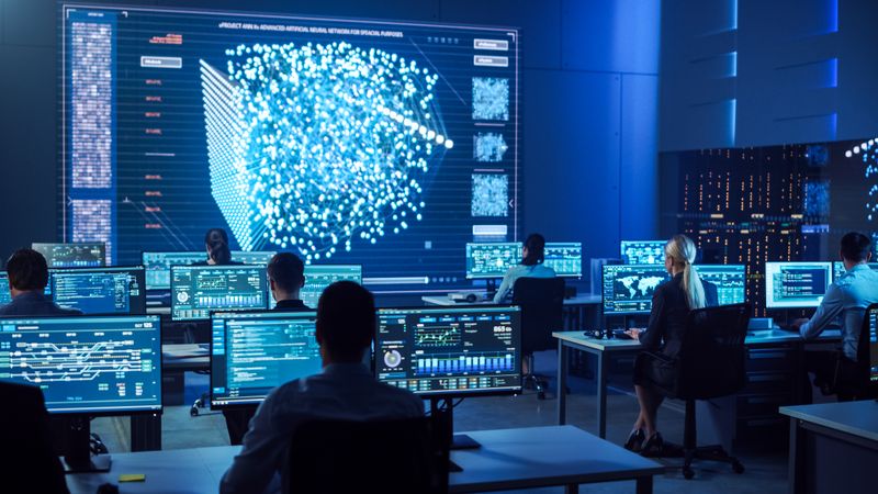Diverse Team Collaborates in a Futuristic Control Room, Analyzing Data on Multiple Screens to Enhance Cybersecurity and Operational Efficiency.