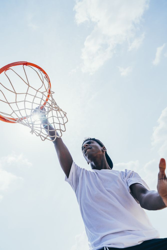 Black sportsman hanging on basketball lap