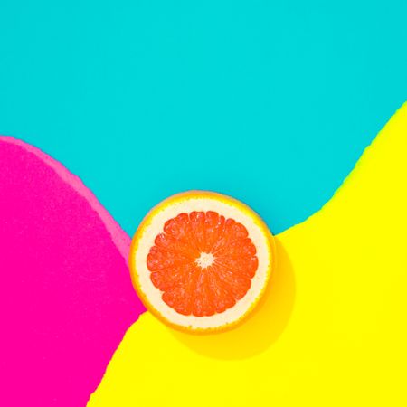 Grapefruit on pattern of ripped paper in vivid colors