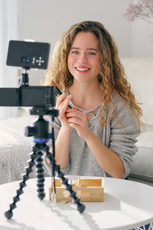 Female vlogger showing makeup brushes to followers