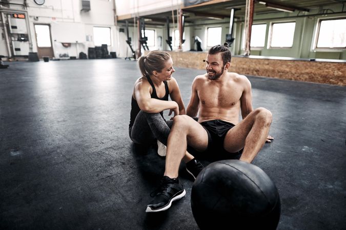 Man and woman sitting on gym floor together