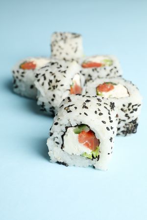 Delicious sushi rolls on blue background. Japanese food