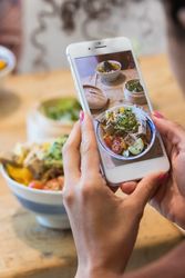 Anonymous woman taking photo of dish in restaurant