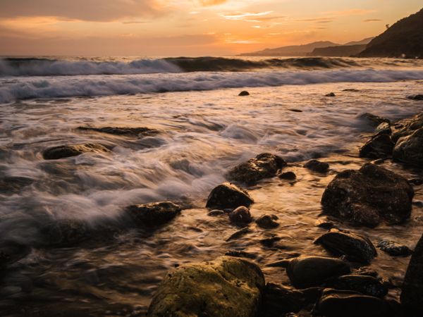 Stony seashore and waves at beautiful sunset