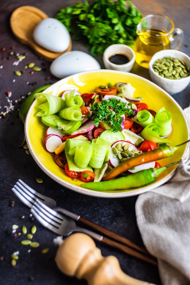 Healthy raw salad with freshly chopped vegetables served with nuts and garnish