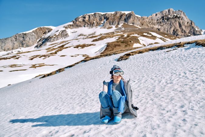 Content boy sitting on snowy hill