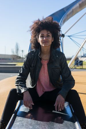Woman with afro hair jumping down a slide.