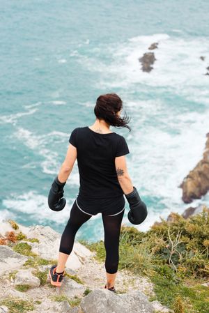 Anonymous female boxer on cliff