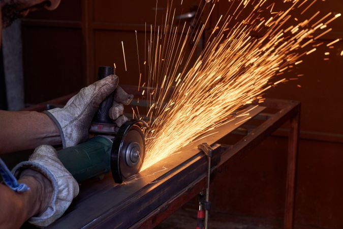 Crop male carpenter cutting metal using special equipment in wor
