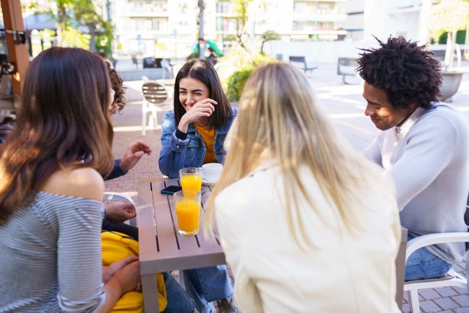 Woman laughing with her friends at an outside table