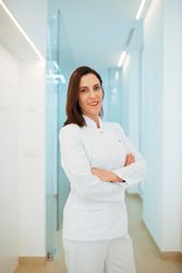 Confident dentist in uniform with crossed arms looking at