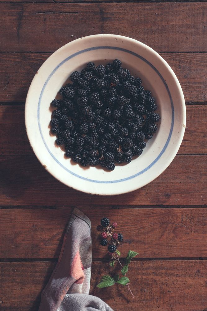 Ripe blackberries garnished by leaves in bowl