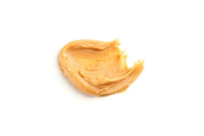 Creamy peanut butter isolated on light background. A traditional product of American cuisine