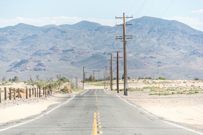 Asphalt road at scenic mountain valley and power line