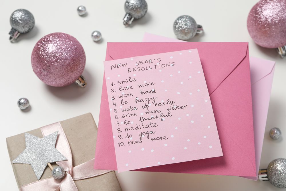 Gift boxes, paper with list and decorations on light background, top view