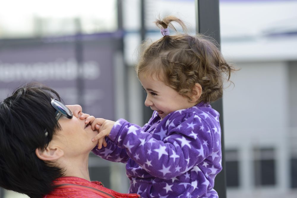 Cute girl with her hands on her mother’s mouth