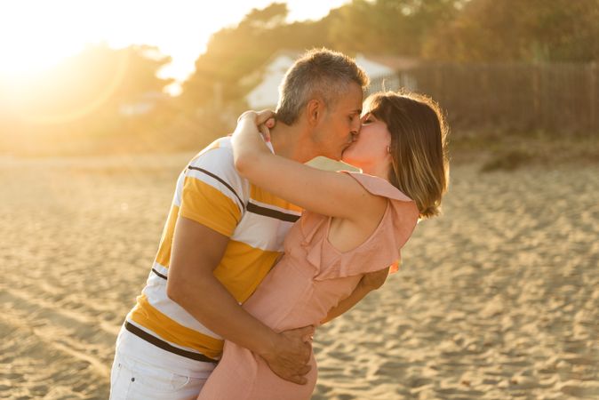Laughing couple hugging on sandy beach