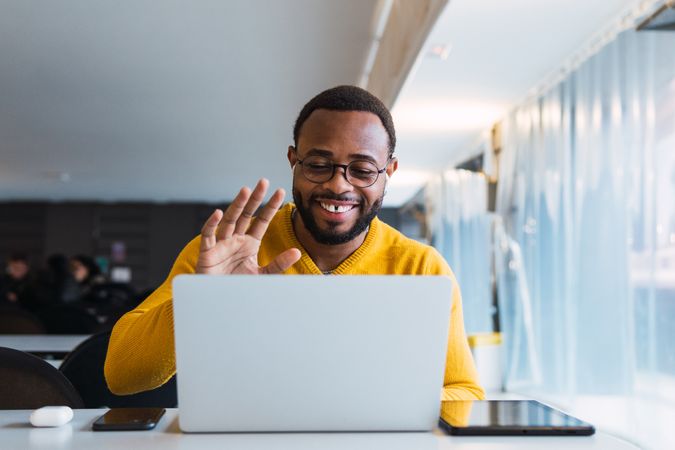 Smiling Black man calling on laptop in workspace
