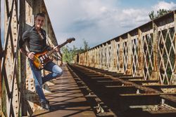Man with guitar standing on bridge