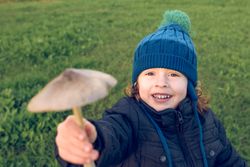 Cheerful boy showing mushroom in nature