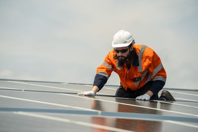 Male engineer checking solar cell  or photovoltaic cell by electronic device installed on the roof of the factory. Technician worker repair or inspect the system. Industrial renewable energy concept