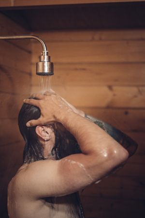 Man taking shower in wooden bathroom