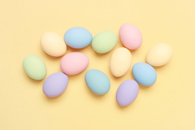 Colorful pastel eggs scattered  on yellow background