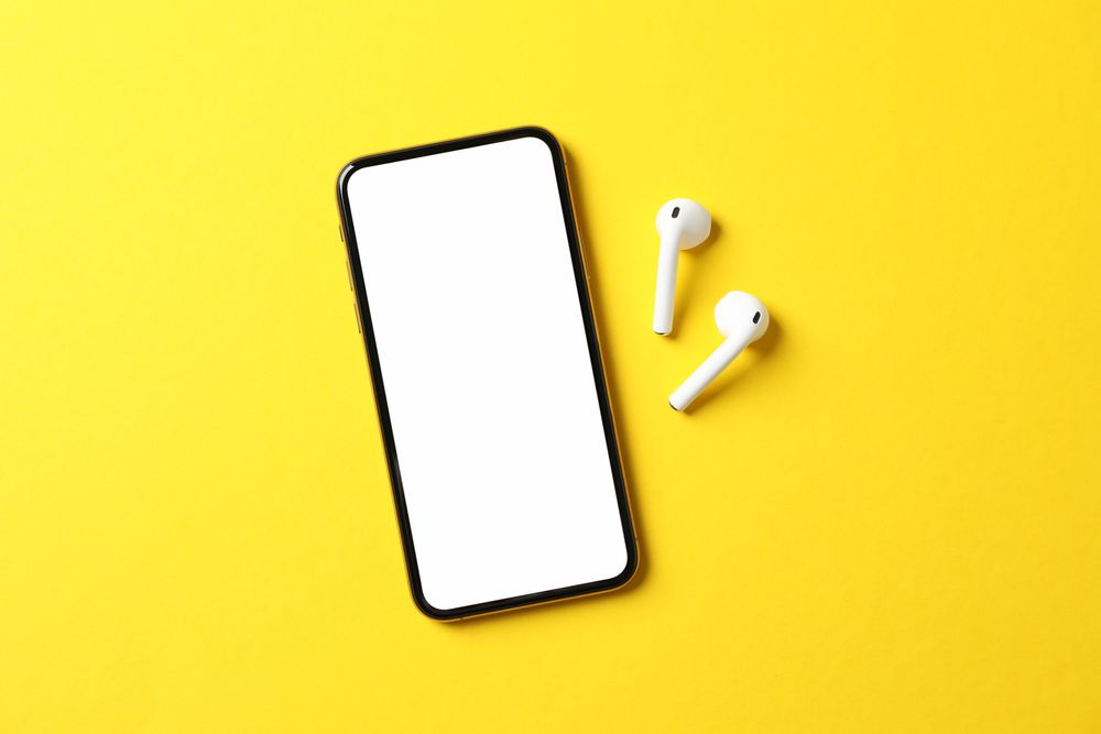 Phone with empty screen on yellow background, top view