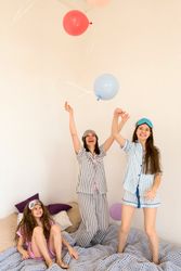 Woman and girls joyfully tossing balloons in air at home