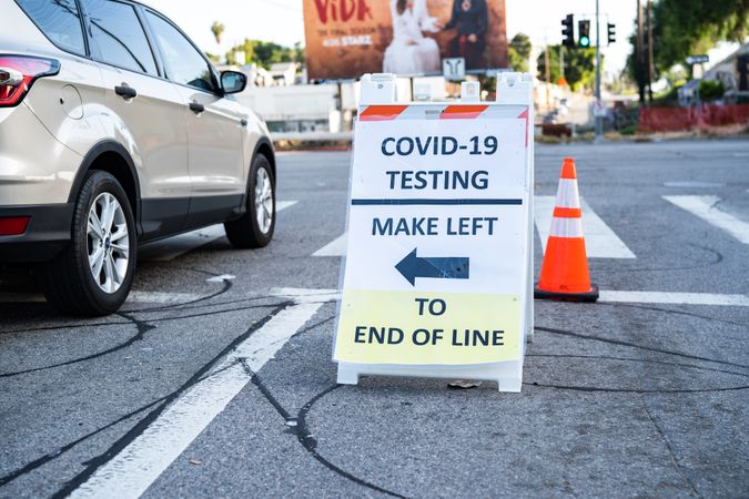 Car next to sign indicating where to line up for free public COVID testing
