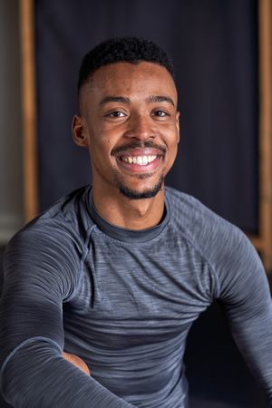 Photo portrait of a Black male with sport clothes and slippers and ballet in a dance academy