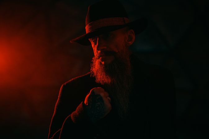 Portrait of middle aged man with fedora hat in red lit studio