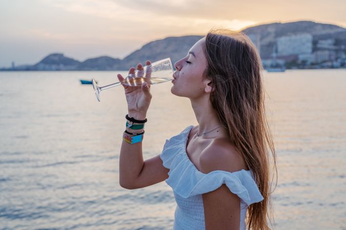 Young woman enjoying wine near sea