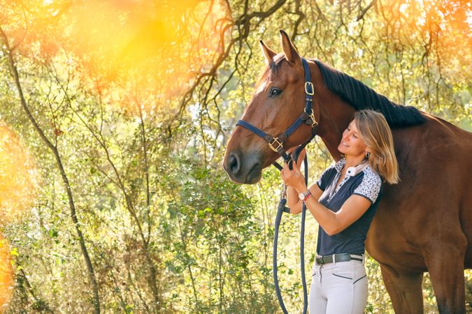 Horsewoman adjusting bridle on horse