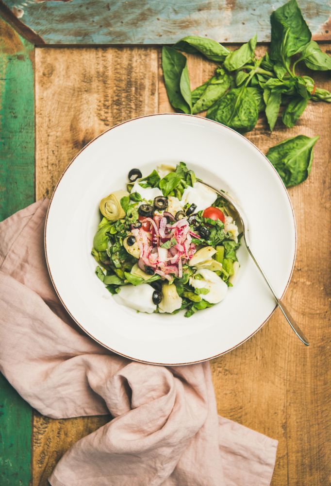 Artichoke salad in bowl, on wooden background with green trim