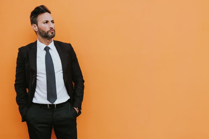 Adult stylish man in costume near orange wall