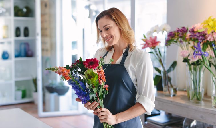 Happy female florist creating bouquet of flowers at her shop