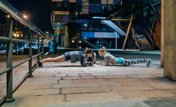 Women's sport team doing plank exercises training in city at night