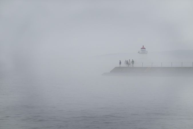 Group of people walking to to a lighthouse on a foggy day in Two Harbors, Minnesota