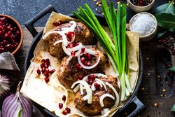 Looking down at Georgian plate of abkhazura meat cutlets with pomegranate seeds and onions