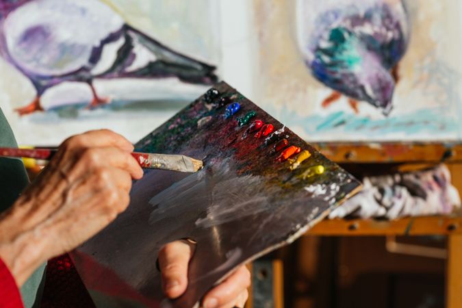 Crop artist with paint palette in workshop