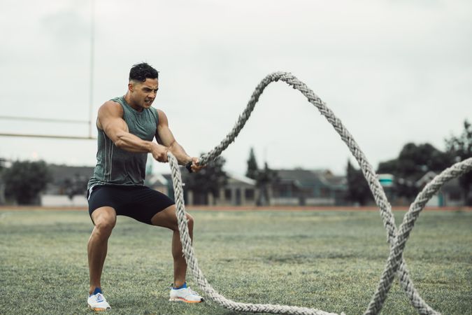 Fit young man working out using two battle ropes