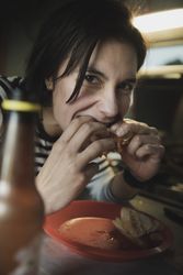 Woman eating sandwich near plate and bottle in camper van