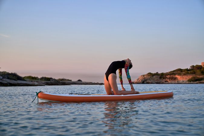 Young woman doing yoga on SUP board