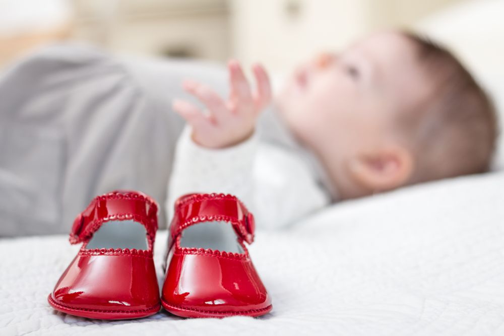 Baby red shoes and babe lying on the background