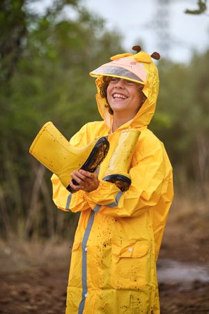 Cheerful boy in waterproof clothes in forest