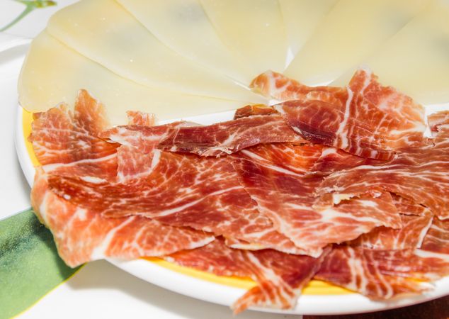 Typical spanish tapa with slices of serrano ham and manchego cheese