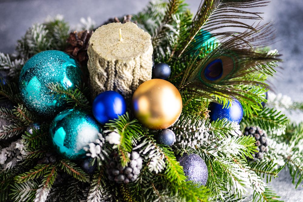 Side view of Christmas festive centerpiece with candle in pine arrangement with ornaments